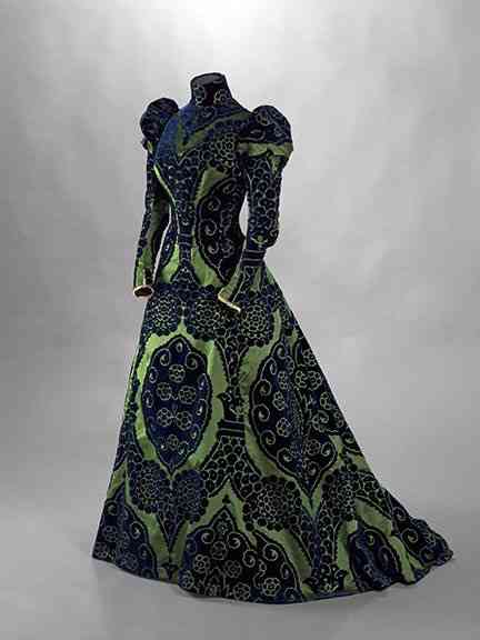 Este exótico vestido, também de Worth, era um "tea gown", como explica o letreiro da mostra, ou um "vestido de chá"... Verde esmeralda, cor preferida de Élizabeth, e azul pavão, ele é de seda, veludo e "renda valenciana" é outra atração de seu guarda-roupa!